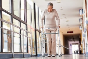 elderly woman alone with a walker in a hallway