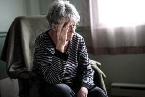 sad, elderly woman, sitting alone in her nursing home room